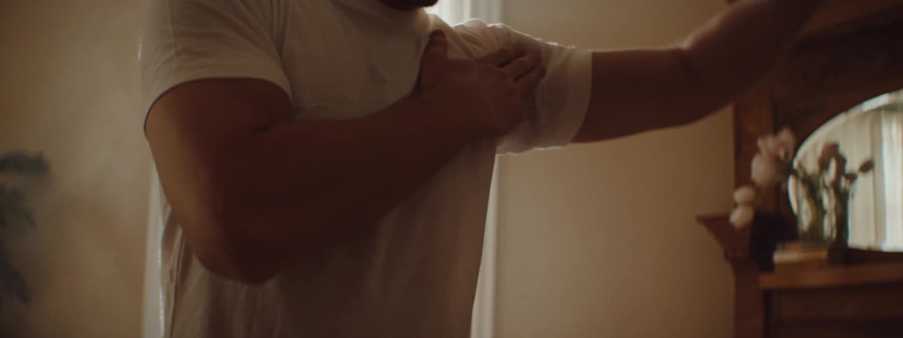 A man in a room with smoke stretching with a wall and window in the background