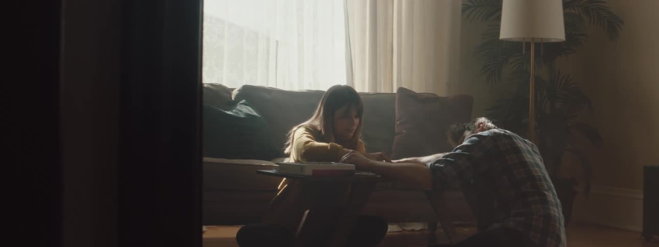 Couple sit on floor in living room playing game on coffee table