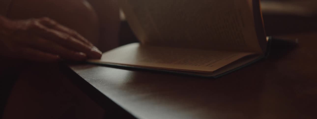 A person is sitting by a table and flipping through pages in a book