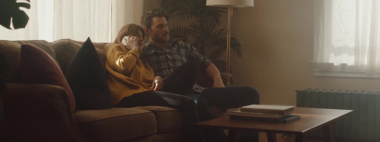 Husband and wife are sitting on the couch together in their living room