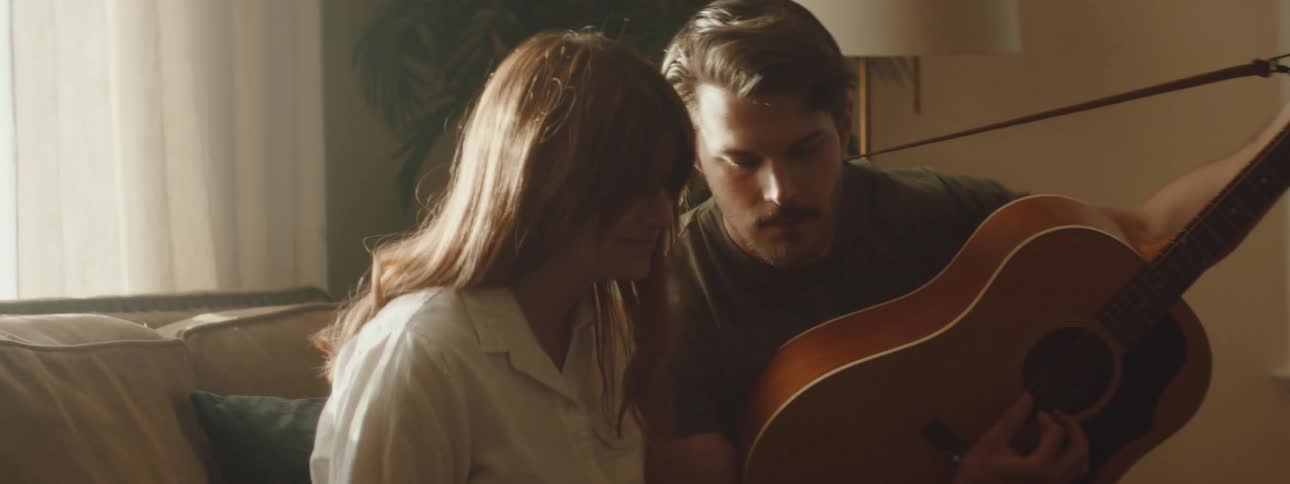 A man playing a guitar for a woman