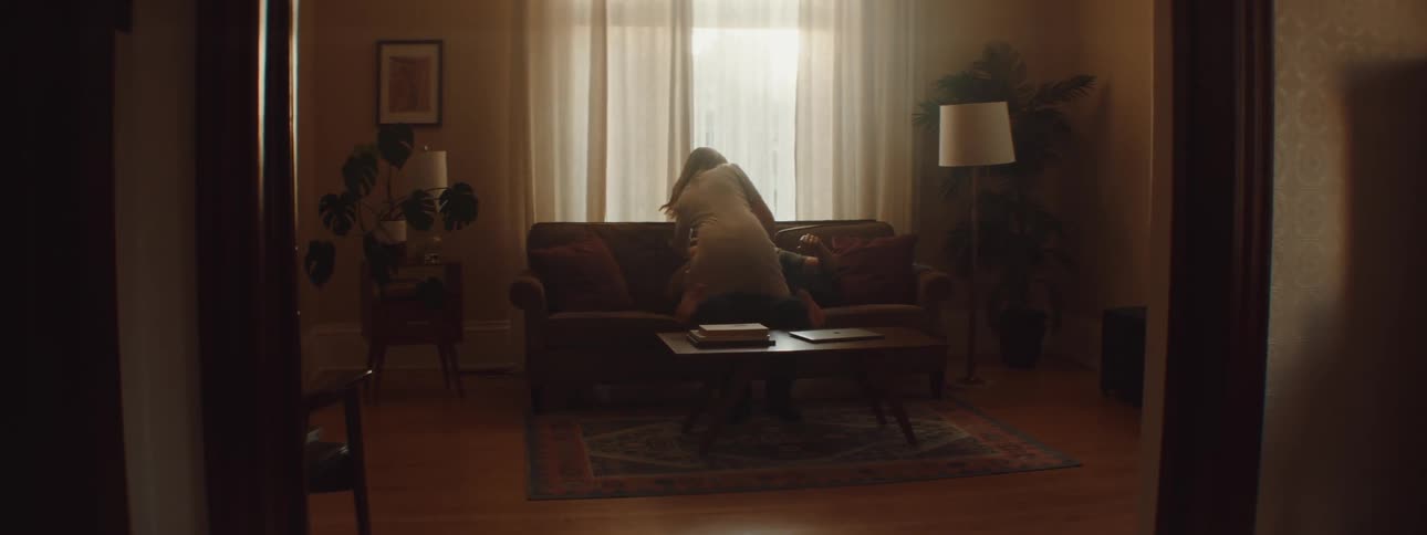 A wife walks into a room and shows affection to her husband