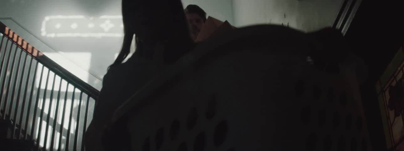 Three people carry boxes and a laundry basket down a flight of stairs