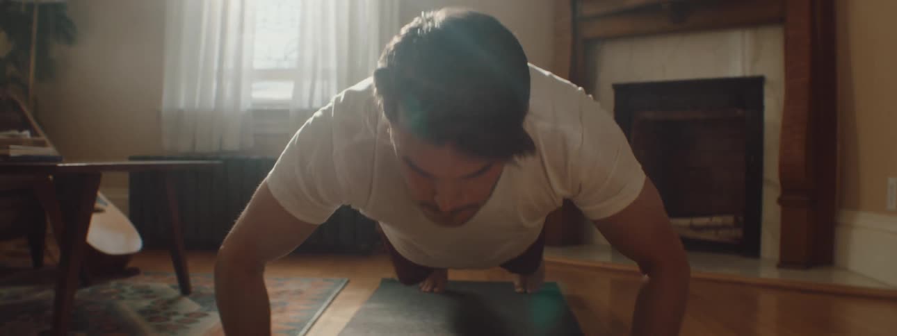Man doing push ups over a mat on the floor of the living room at home