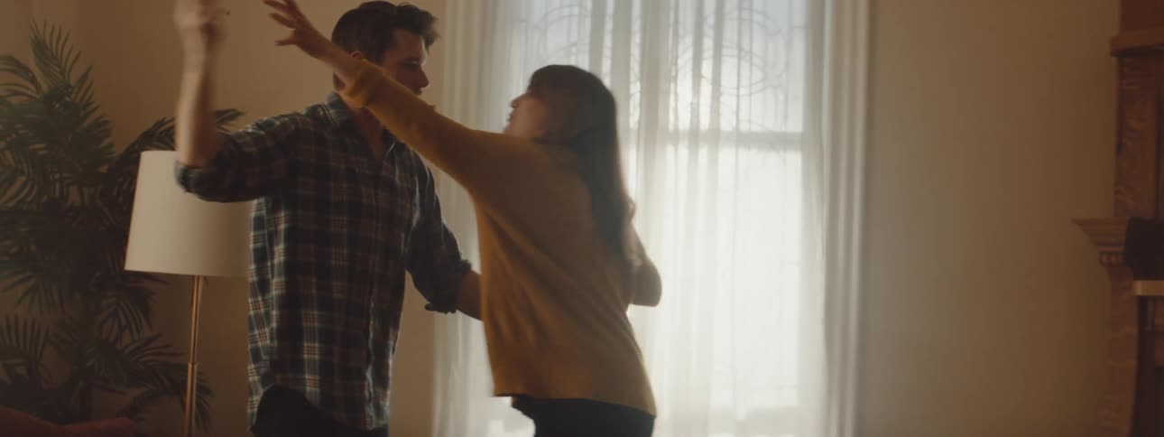 A man hugs a woman and hides a cell phone behind her back then she grabs the phone