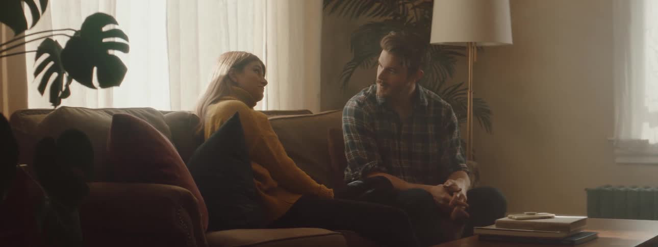 A man and woman are talking and sitting on a couch