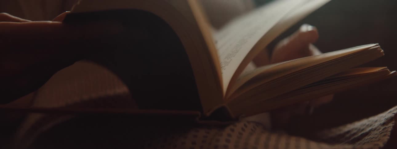 A woman in a houndstooth skirt flips back and forth through the pages of a book