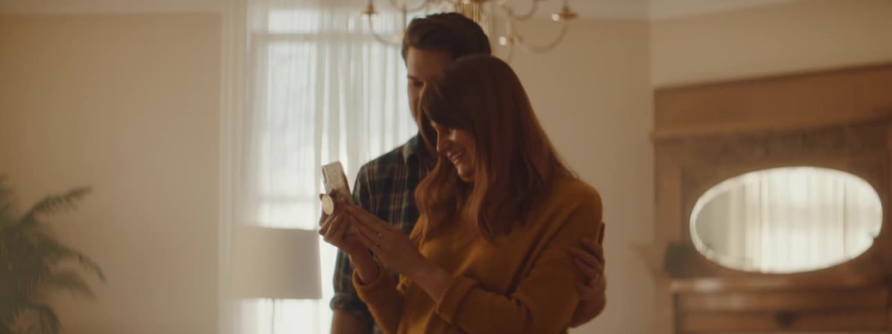 Husband and wife are talking on the phone and waving at someone
