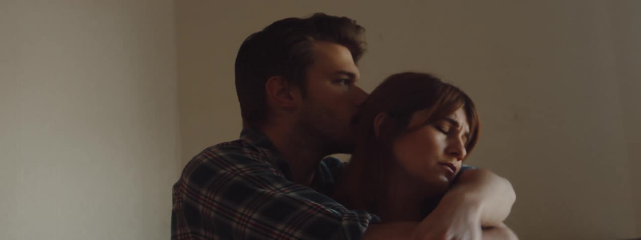Man comforts a sad woman with hugs and kisses in a room at home