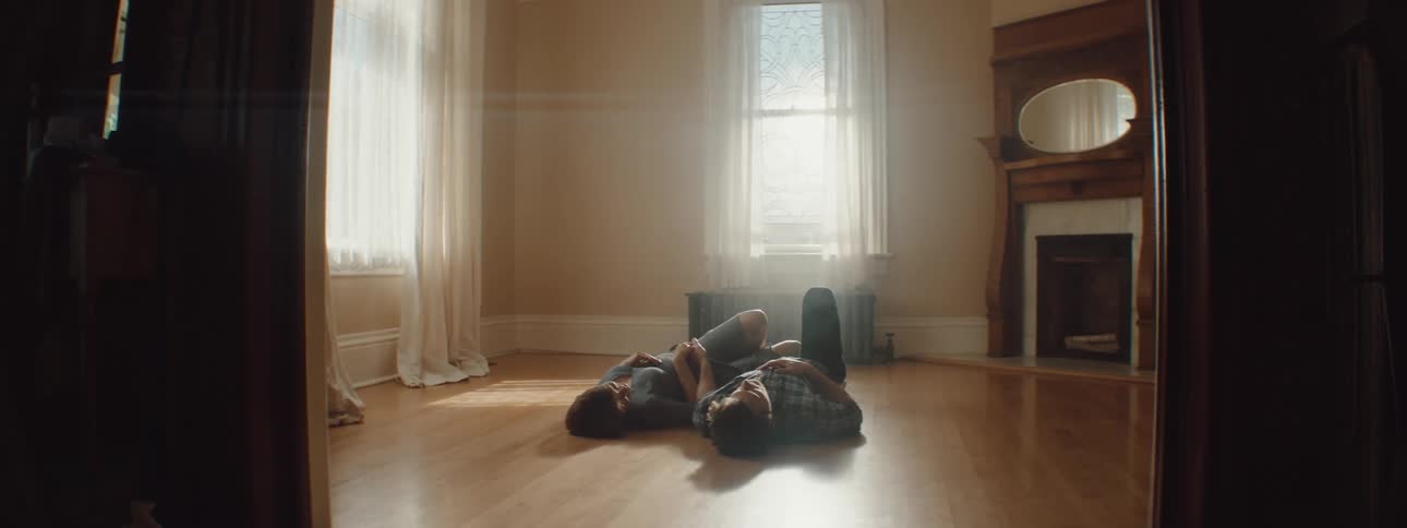 Man and woman lies down on the floor in empty room