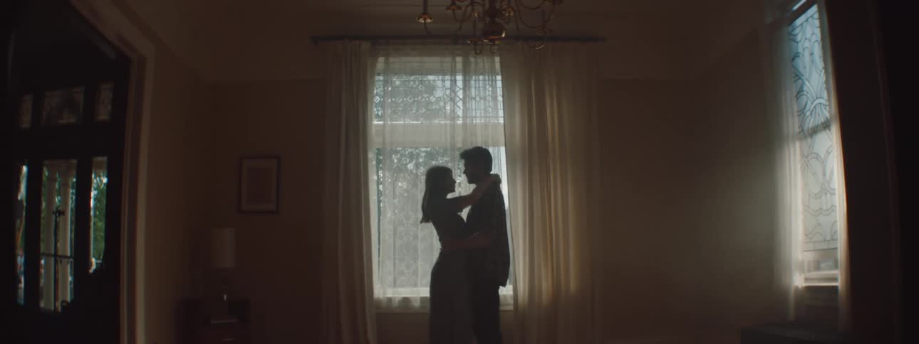 A man and woman hug one another in a living room