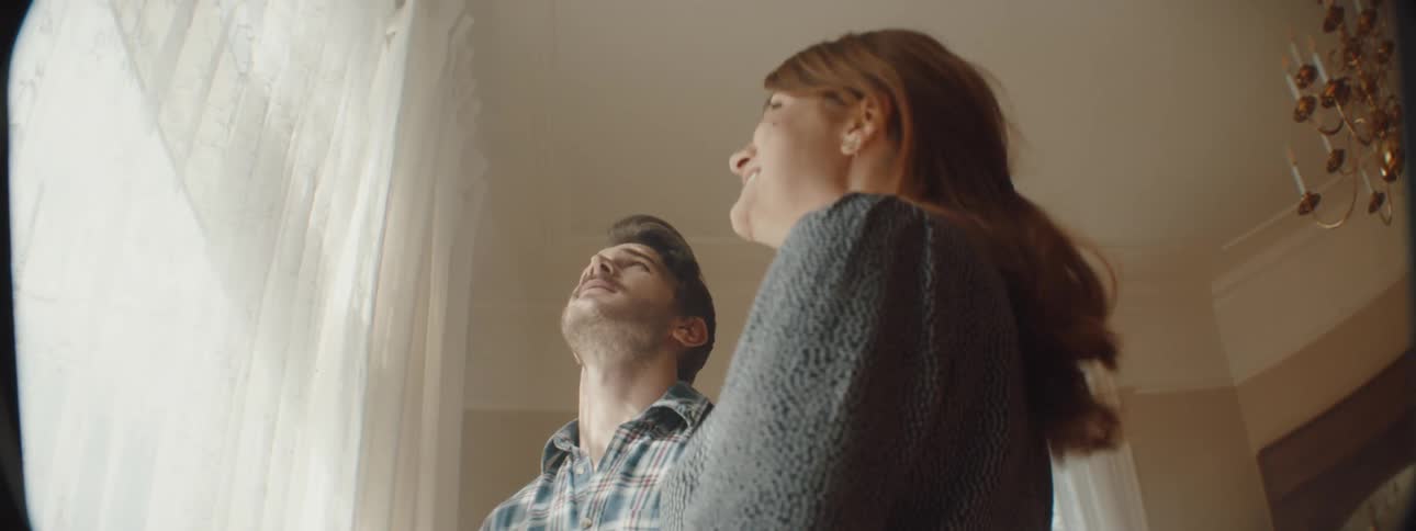 Man and woman look at the curtains in the living room at home
