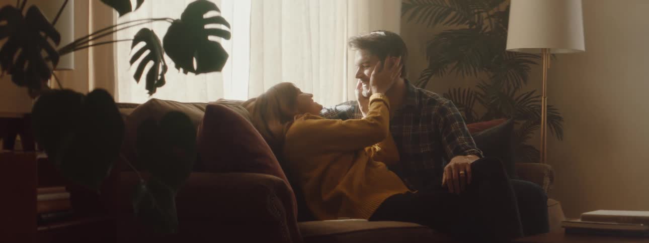 Husband and wife are showing each other affection while sitting on a couch