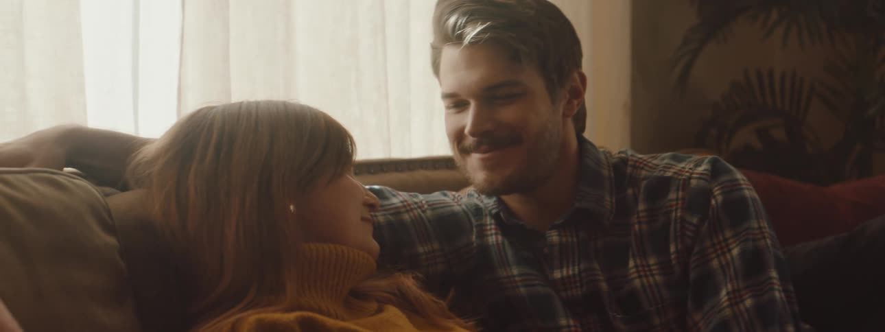 Young happy couple playfully hugging each other in the couch at home