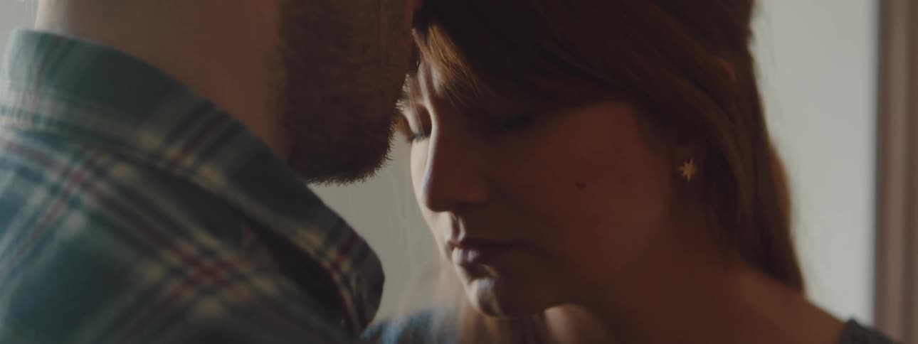 Husband is holding his wife close and standing indoors