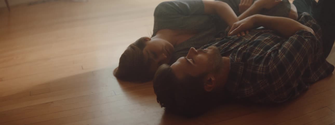 Couple lies on wooden floor next to each other smiling