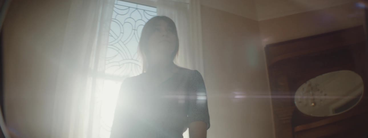 A woman is walking around her house and looking at furniture