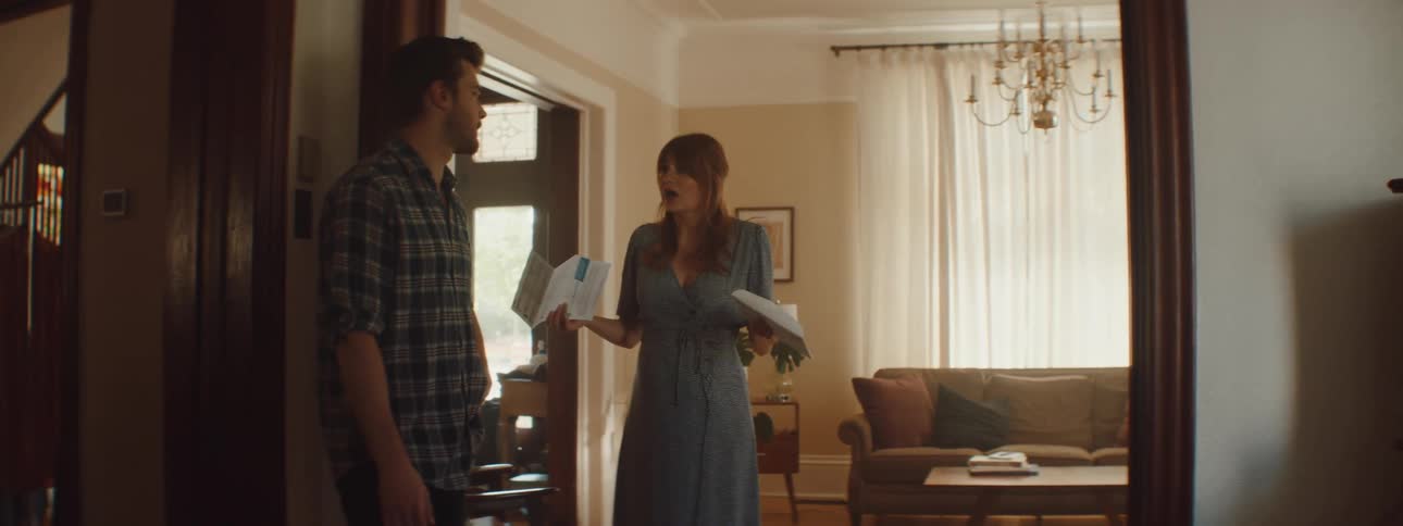 A couple argue while the woman shows a bill