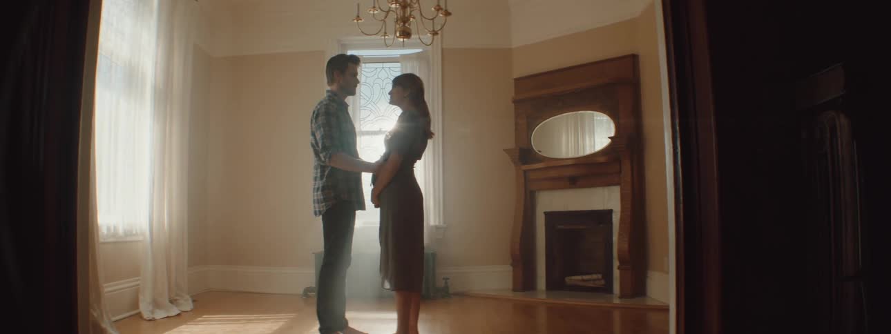 Husband and wife are hugging and standing in an empty room