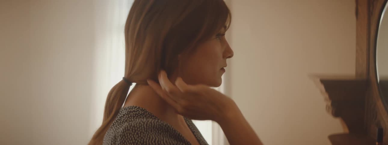 A woman is looking in a mirror and fixing her hair