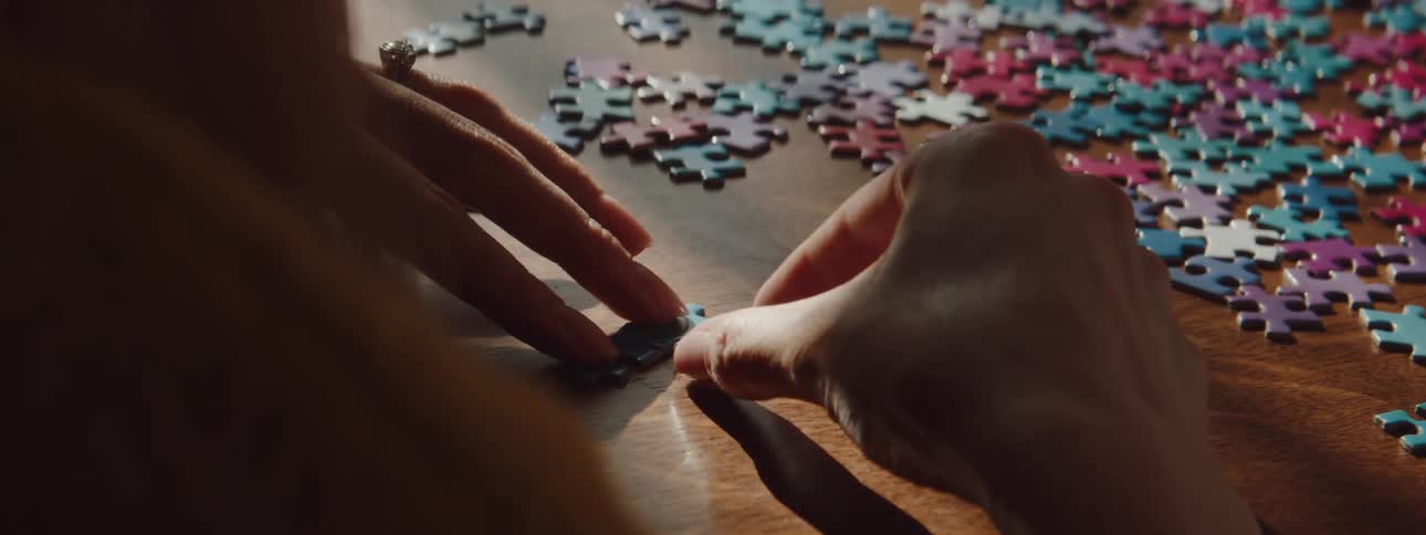 Woman connects the pieces of a jigsaw puzzle