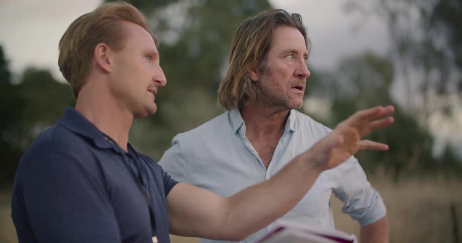 Two men talking outdoors looking at a piece of paper