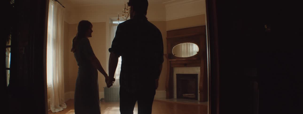 Husband and wife are holding hands and walking into a room together