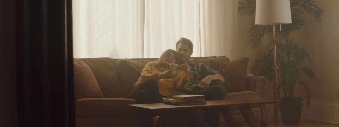 A man and a woman relaxing on a couch together inside of a living room at home