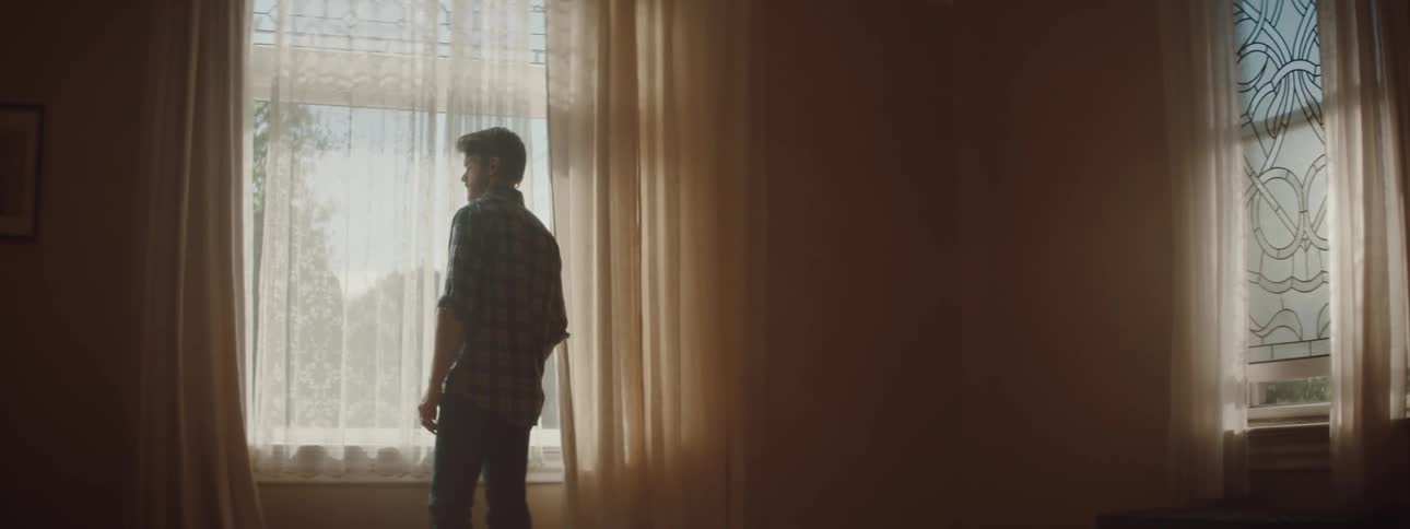 Man peers out of a window on a sunny day