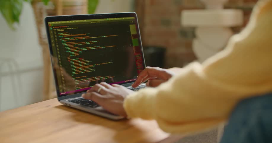 A woman is sitting indoors and typing on laptop