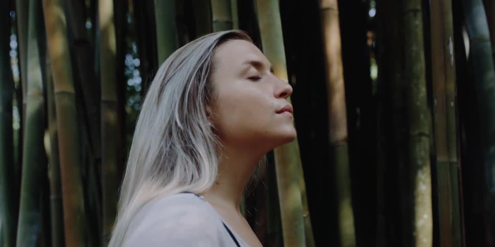 A woman stands by the tall bamboo trees