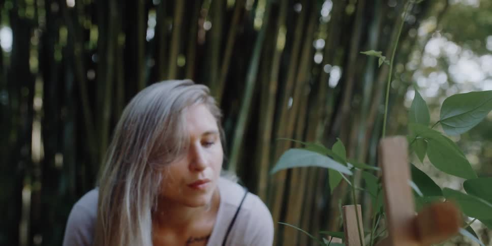 Long haired blonde woman standing near bamboo plants outdoors