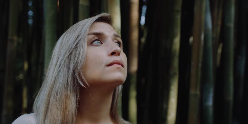 A woman is standing outdoors next to some trees in spring