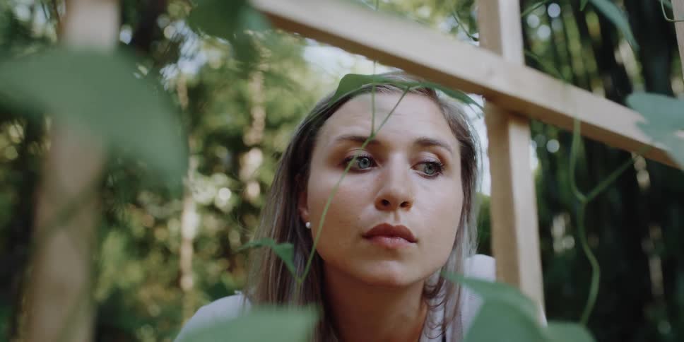 A woman is standing outdoors in a garden of plants