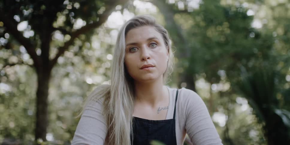 A woman is sitting outdoors in a wooded area