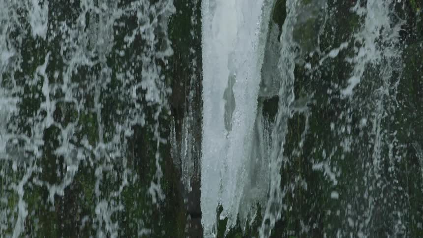 Slow motion tilt down following a massive icicle and cascading droplets of pristine water as they explode outward