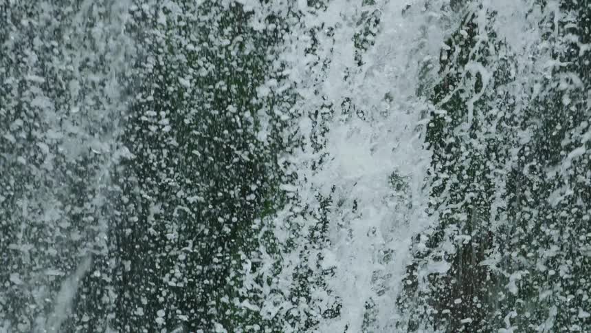 Awesome slow motion tilt down shot of water droplets exploding downwards towards the river below
