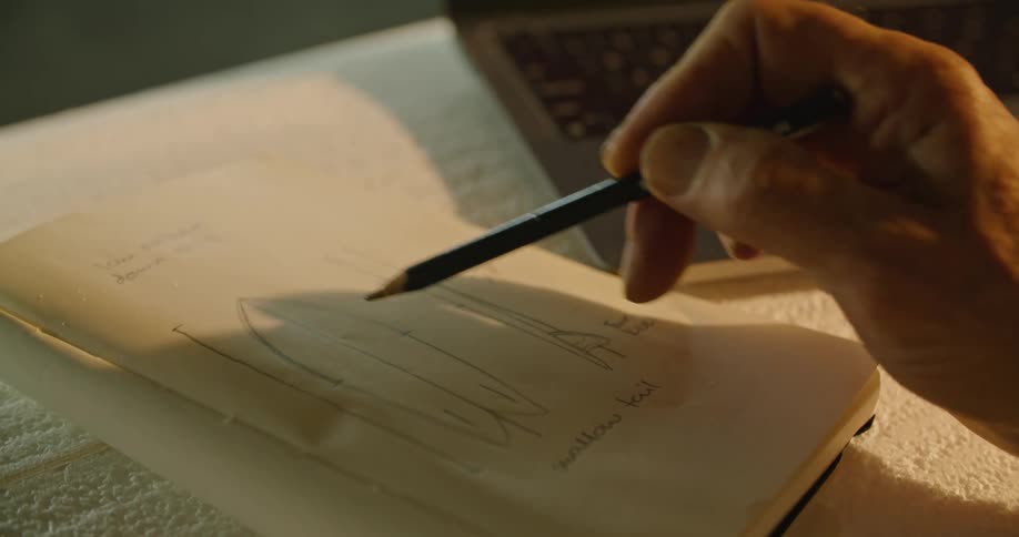 A person is writing on a notepad indoors