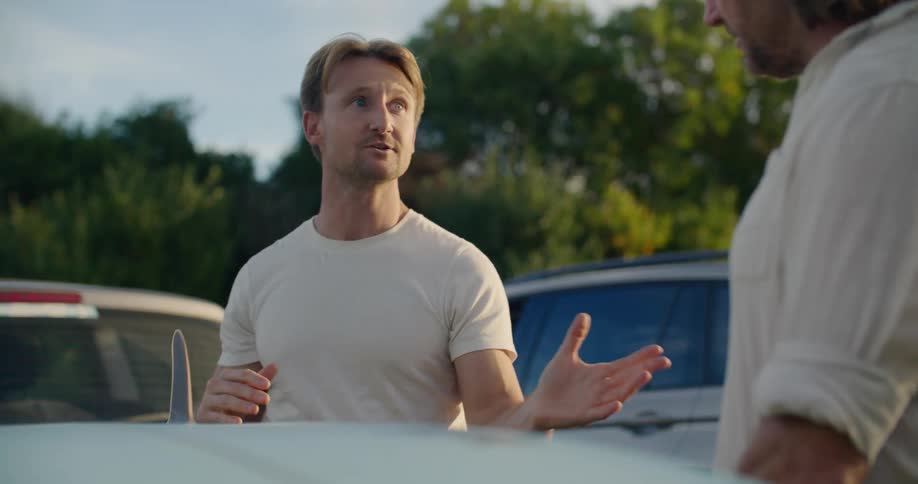 Two friends are standing outdoors in a parking lot together