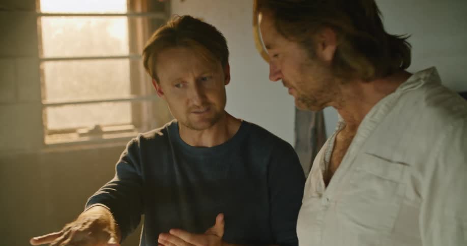 Two men stand together and talk