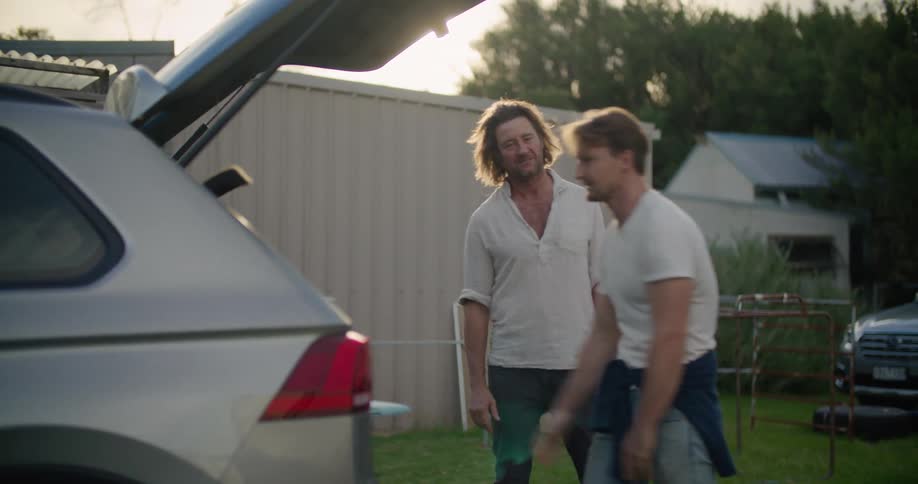 A man loads a surfboard into his car