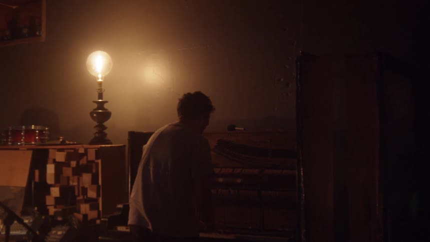 A person playing an old pianola inside a dimly lit room