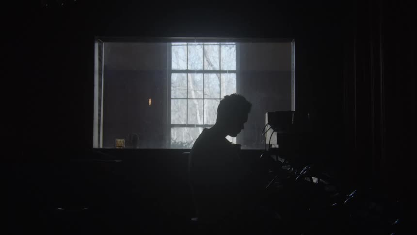 A man is sitting indoors next to a window