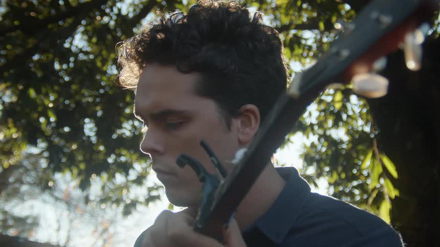 A man is outdoors and playing a guitar in spring