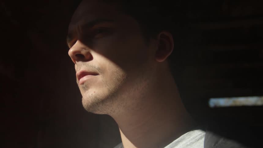 A man is standing indoors and the light is reflecting on him