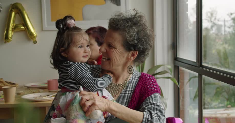 Grandmother playing with her granddaughter at home in a birthday party