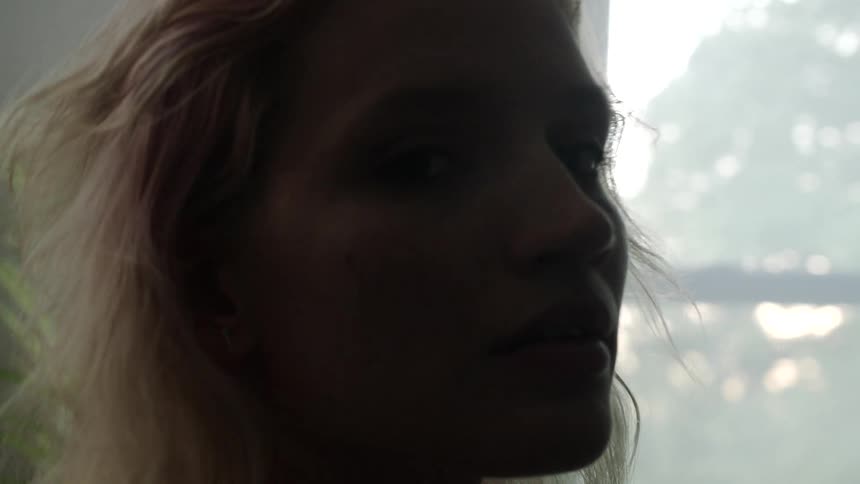 Silhouette of a blonde womans face standing inside a dimly lit room