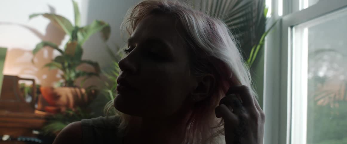 Silhouette of a blonde woman playing with her hair inside a dimy lit room