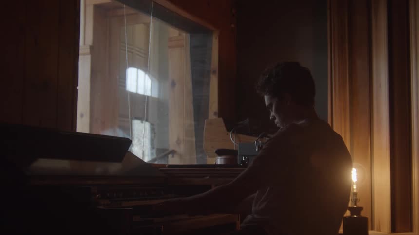 A man is playing the piano in a dark room