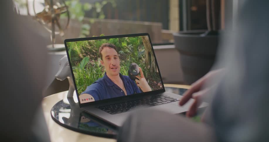 Man holds an object in his hand to show it through a video call on a laptop